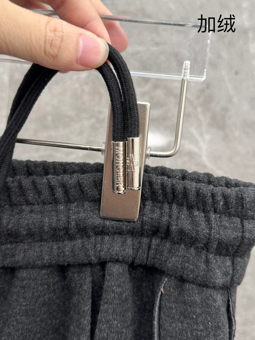 Elastic waistband with metal clasp and drawstring cord on dark grey sweatpants