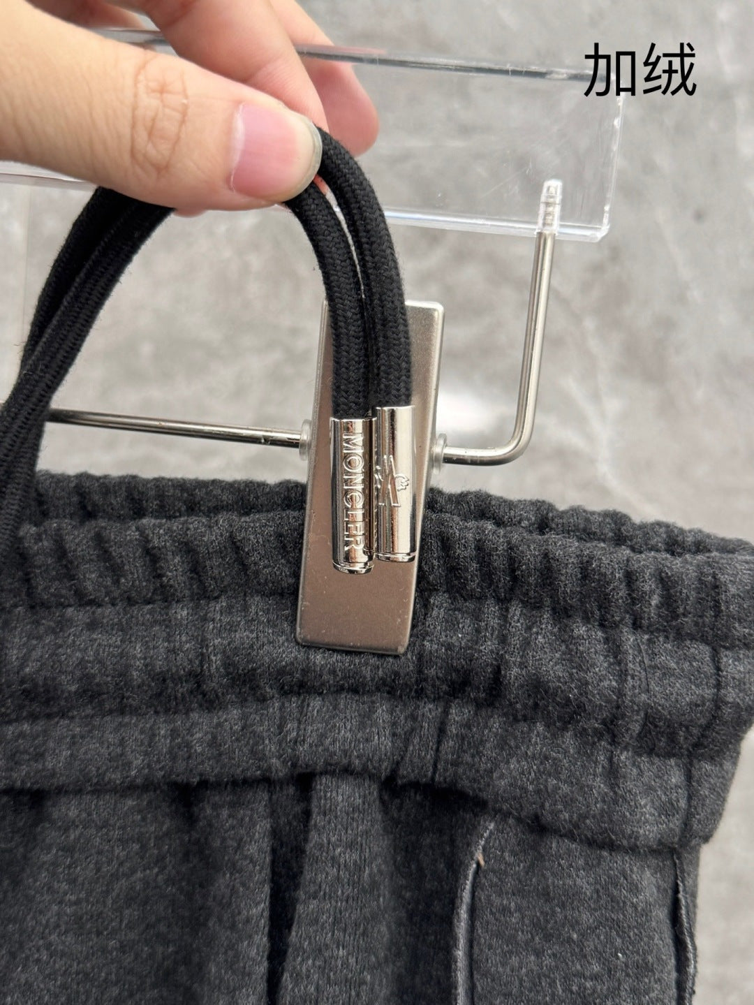 Elastic waistband with metal clasp and drawstring cord on dark grey sweatpants