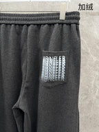 Dark grey sweatpants close-up: ribbed waistband and large side logo patch