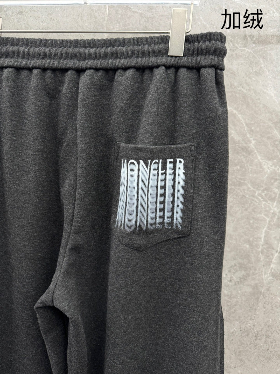 Dark grey sweatpants close-up: ribbed waistband and large side logo patch