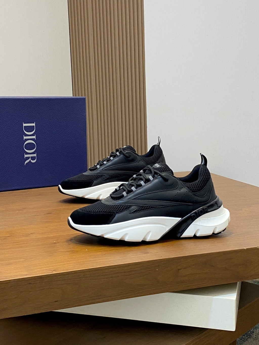 Black Dior sneakers with white midsoles and chunky tread, side view on display