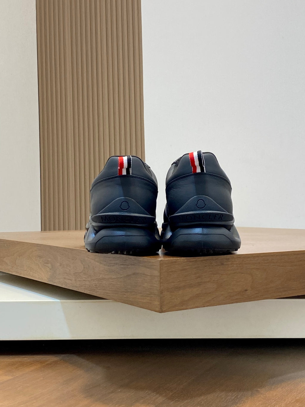 Moncler dark sneakers rear view with red-white heel tabs and molded outsole