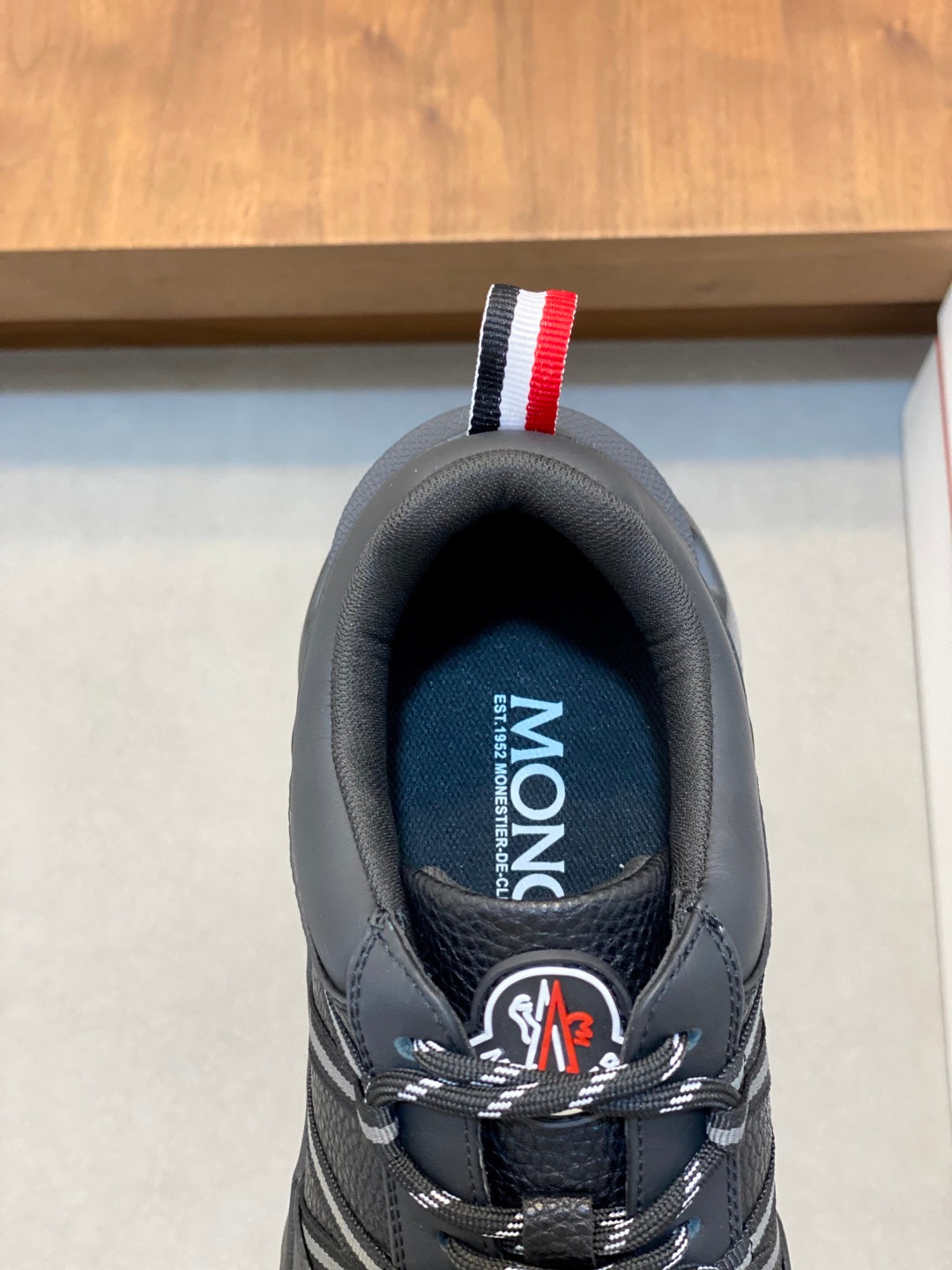 Moncler sneaker tongue close-up with MONCLER label and red-white heel stripe