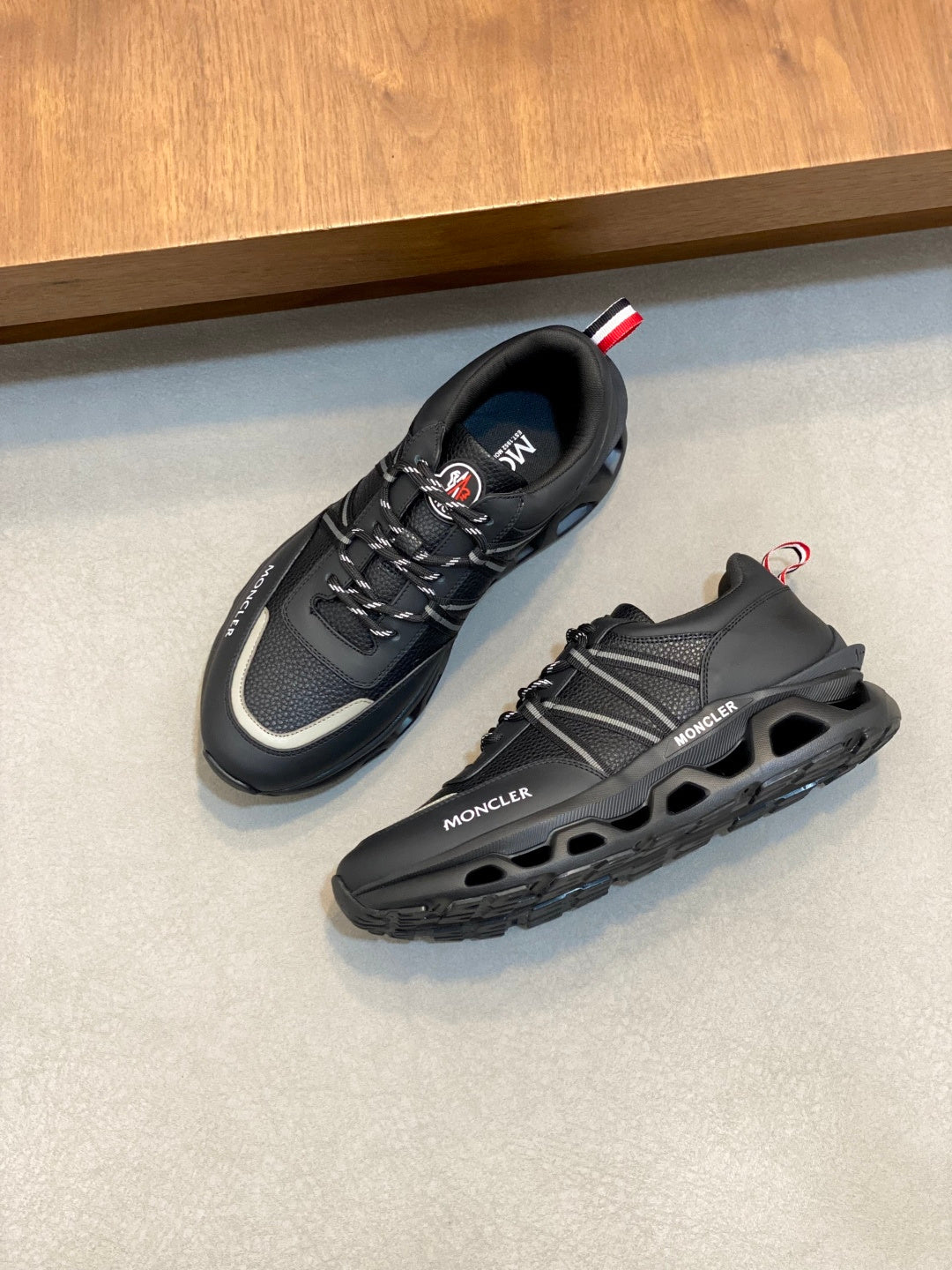 Moncler black low-top sneakers pair with red-white heel detail and tread sole