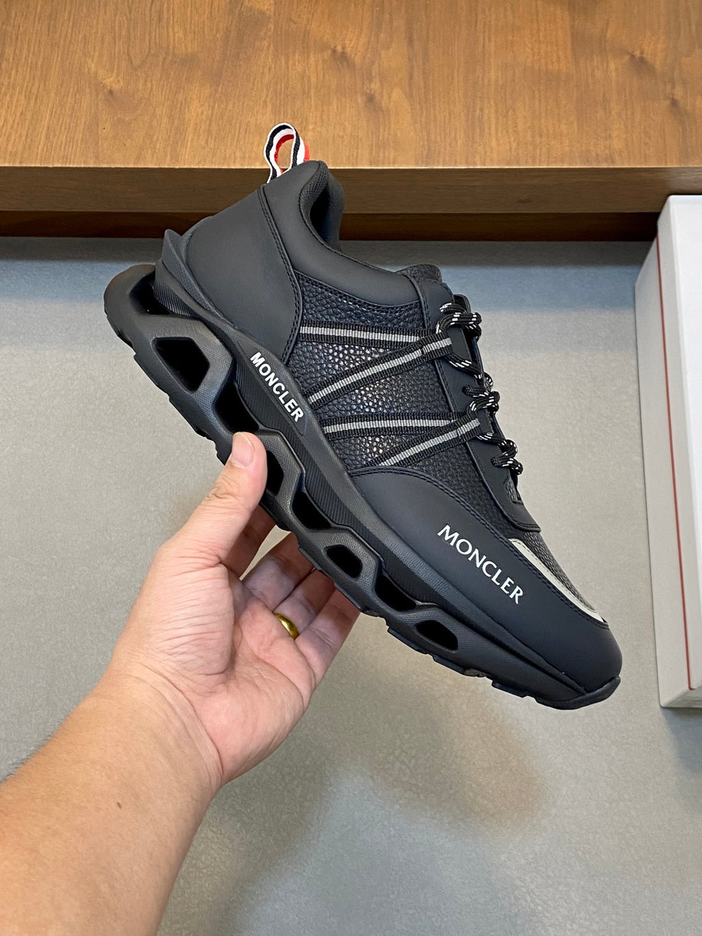 Moncler black low-top sneakers in hand, lace-up with silver side stripe