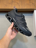 Moncler black low-top sneakers in hand, lace-up with silver side stripe
