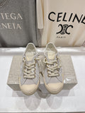 Grey low-top sneakers with white laces, gold star detail, beige rubber sole