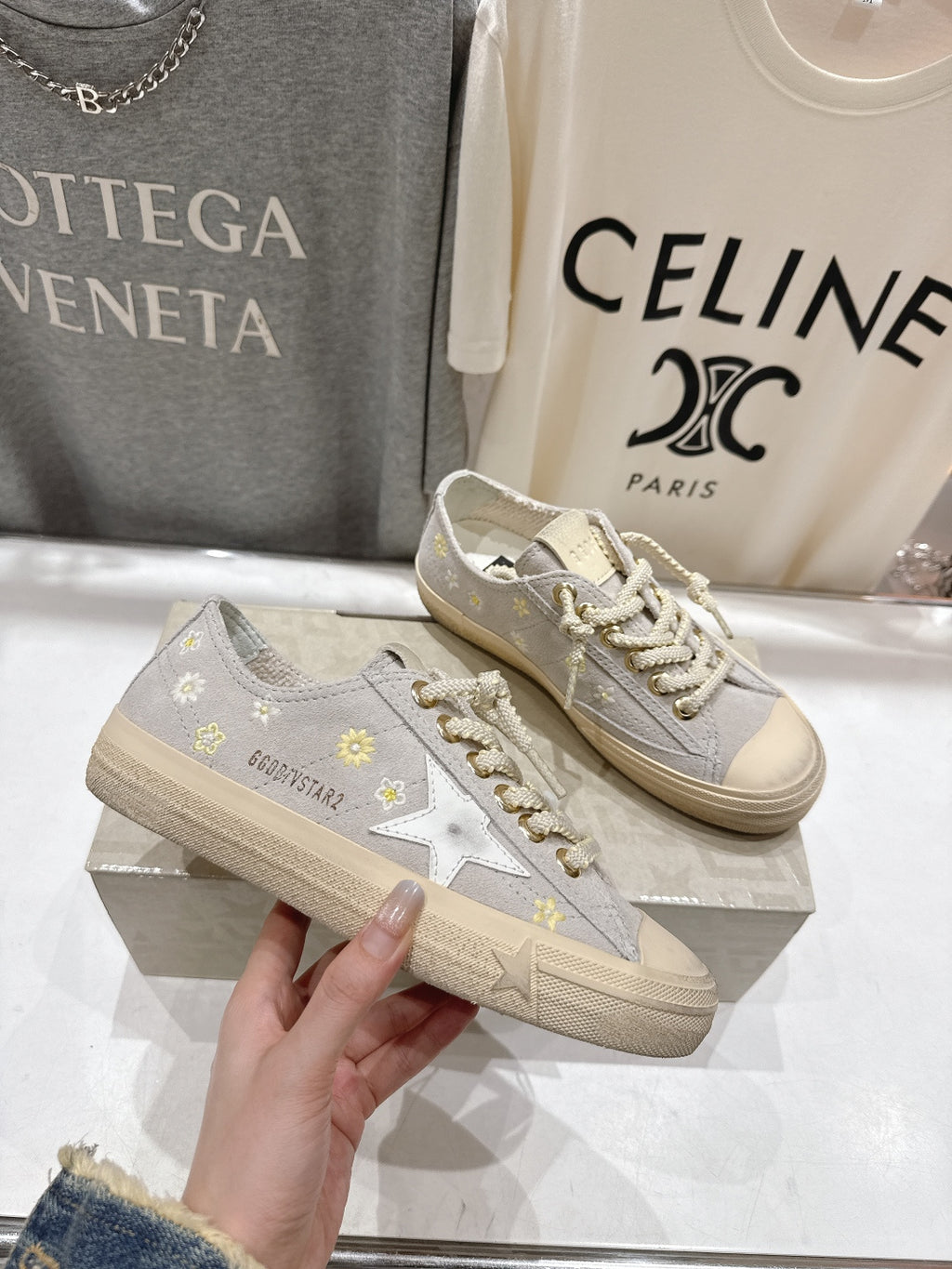 Grey low-top sneakers with white laces, gold star patch and off-white sole