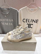Grey low-top sneakers with white laces, gold star patch and beige platform sole