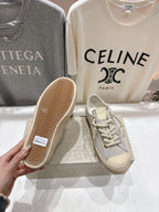 Grey low-top sneakers with beige tread outsole, white lace-up front
