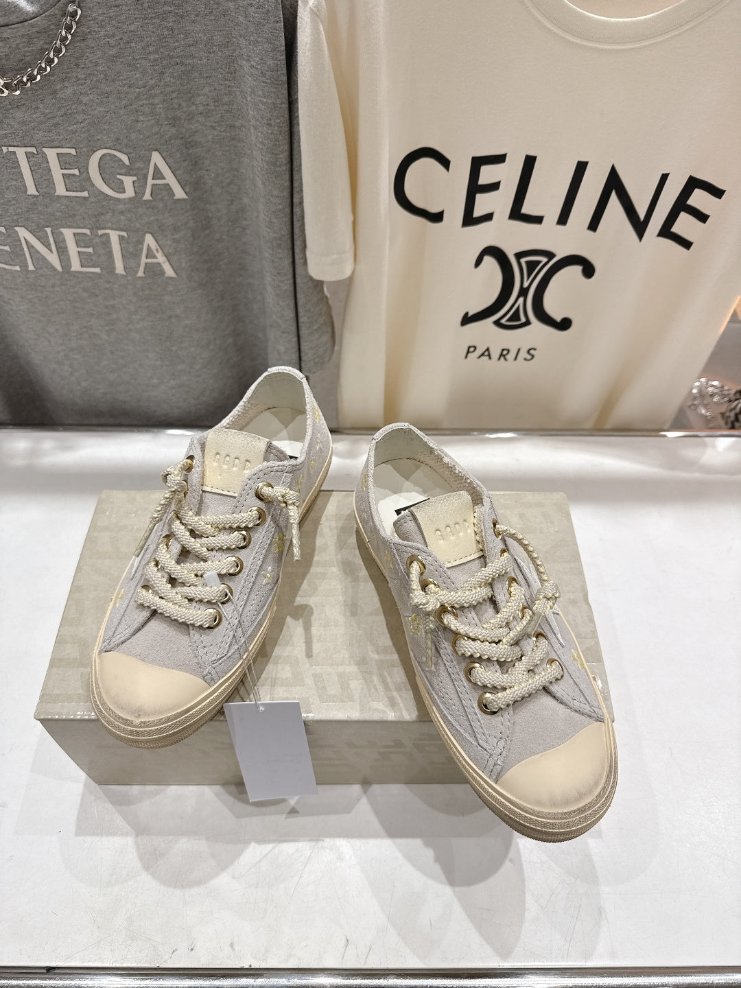 Grey low-top sneakers with white laces and gold eyelets, beige rubber sole