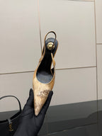 Women’s pointed-toe slingback heel held in black gloves, black and tan speckled finish