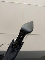 Black shoe outsole and side profile with printed branding, pointed-toe stiletto
