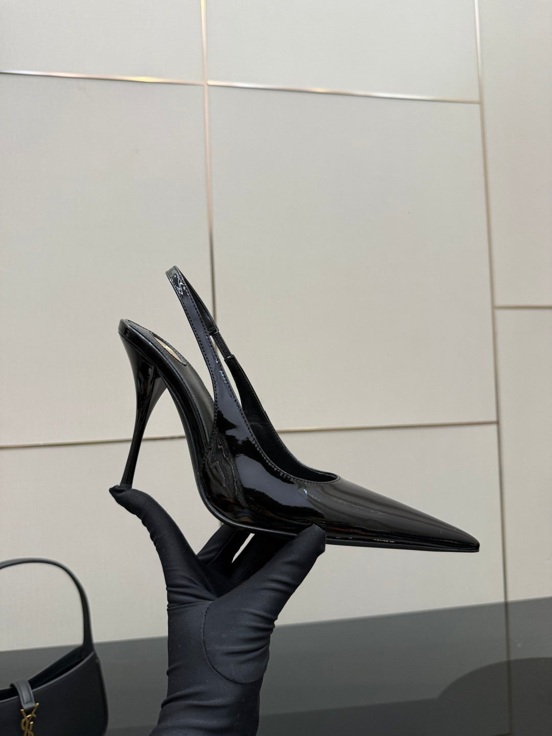 Black patent pointed-toe stiletto heels with ankle strap and glossy shine