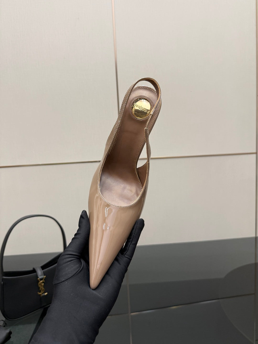 Nude patent leather slingback stiletto heel with gold-tone logo hardware, side view