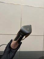 Nude patent stiletto heel with pointed toe, underside view in hand