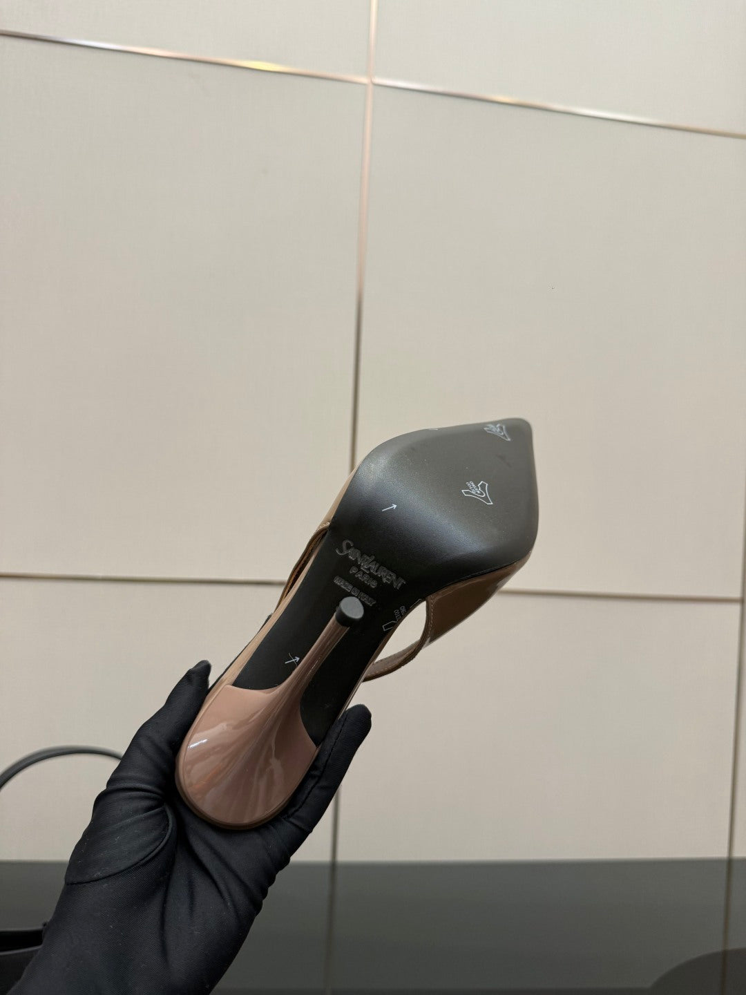 Nude patent stiletto heel with pointed toe, underside view in hand