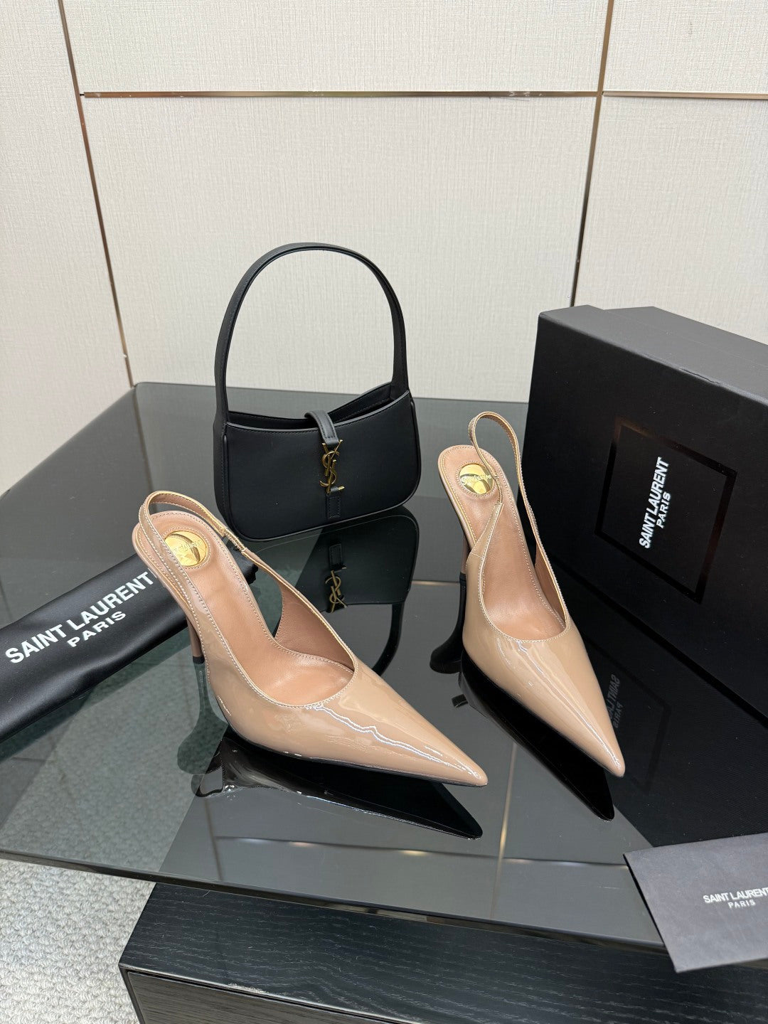 Nude patent leather pointed-toe stiletto heels with gold-tone logo detail, side view