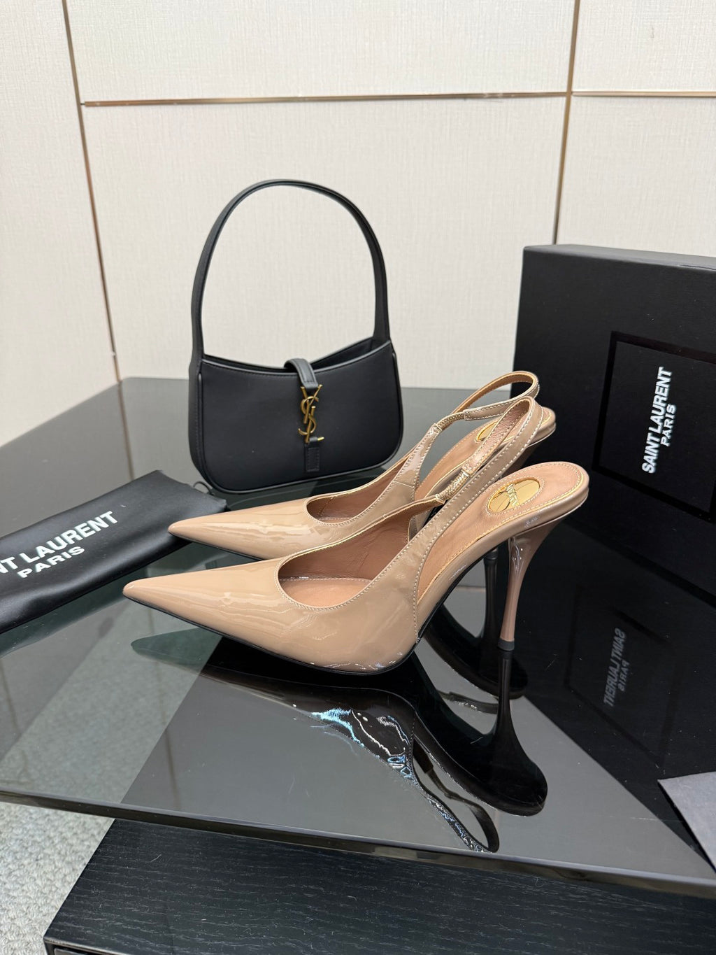 Nude patent leather pointed-toe stiletto heels with gold-tone logo detail, pair