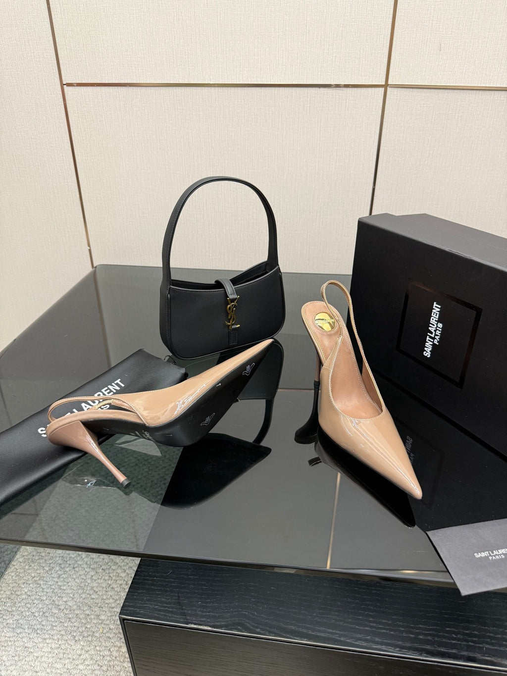 Nude patent pointed-toe stiletto heels with gold-tone logo detail, plus black shoe