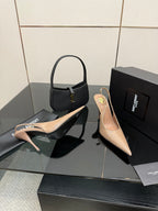 Nude patent pointed-toe stiletto heels with gold-tone logo detail, plus black shoe