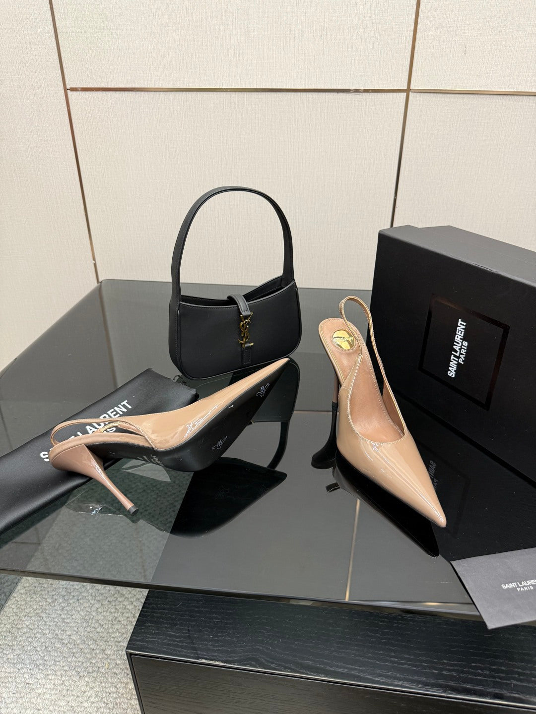 Nude patent pointed-toe stiletto heels with gold-tone logo detail, plus black shoe
