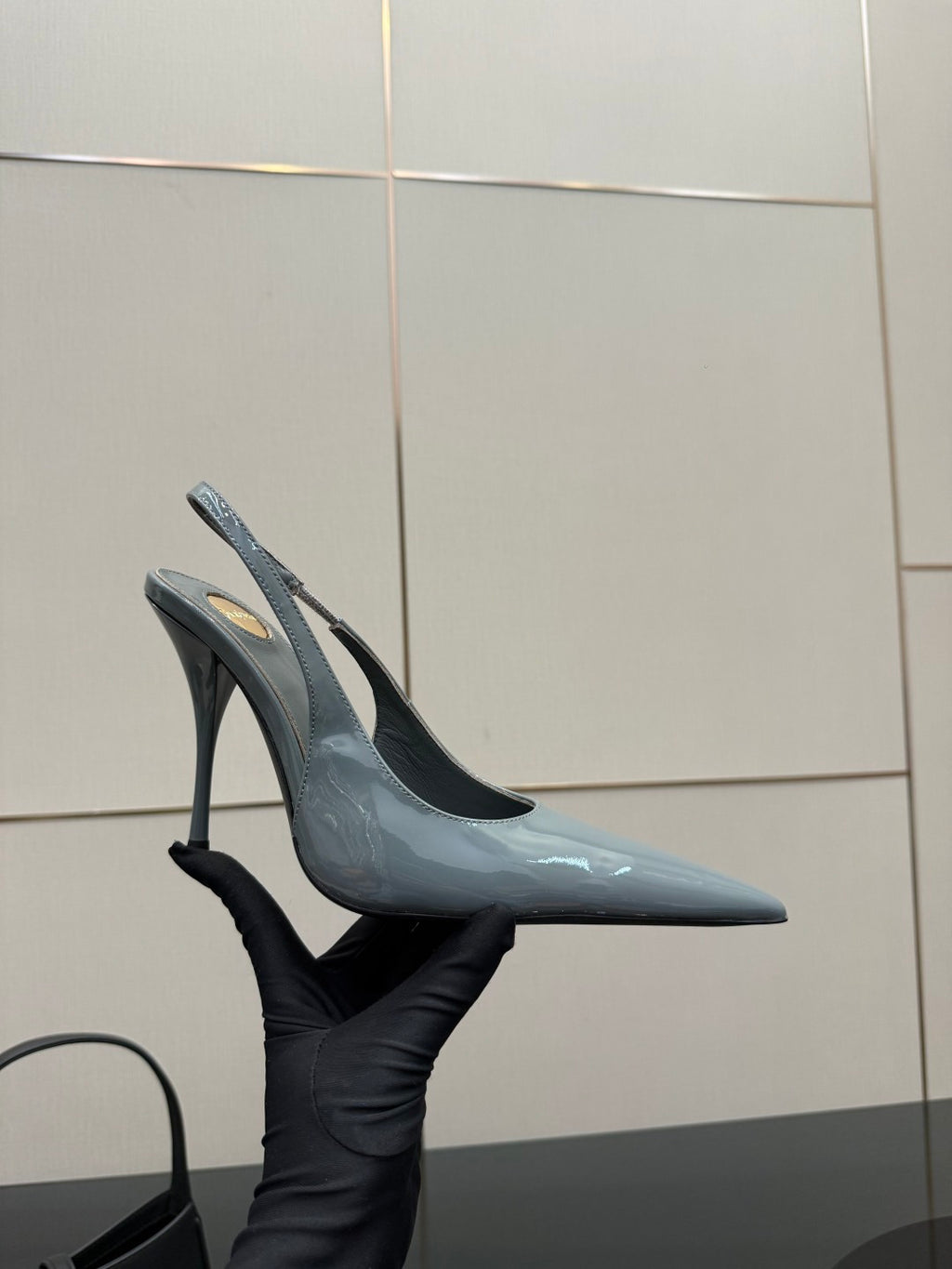 Light blue glossy pointed-toe slingback stiletto heels held in hand, high heel.