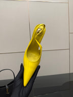 Yellow pointed-toe high-heel slingback shoe held upright, side view