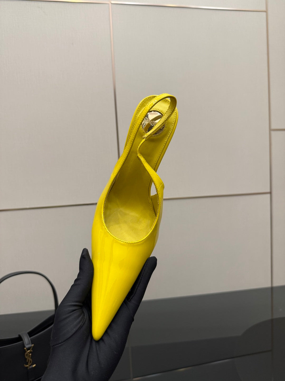 Yellow pointed-toe high-heel slingback shoe held upright, side view