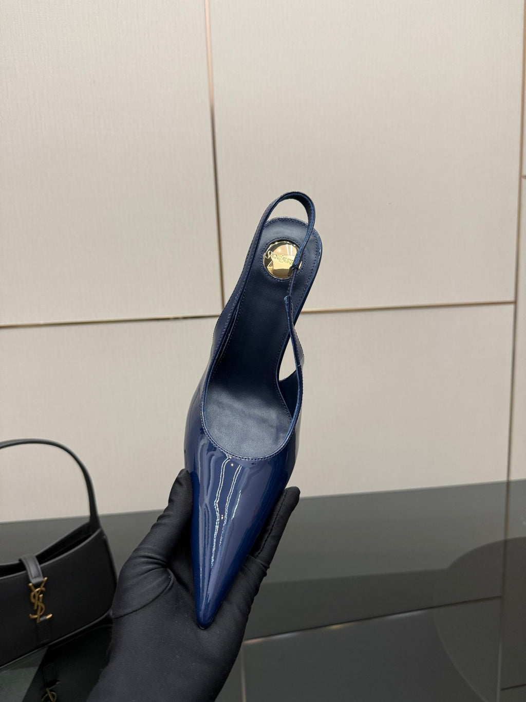 Ladies’ glossy blue pointed-toe high-heel pump held up, back view