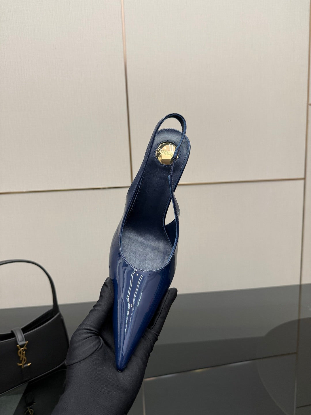 Ladies’ glossy blue pointed-toe high-heel pump held up, back view