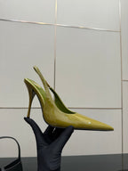 Lime-green patent pointed-toe stiletto heel, side view held by a glove
