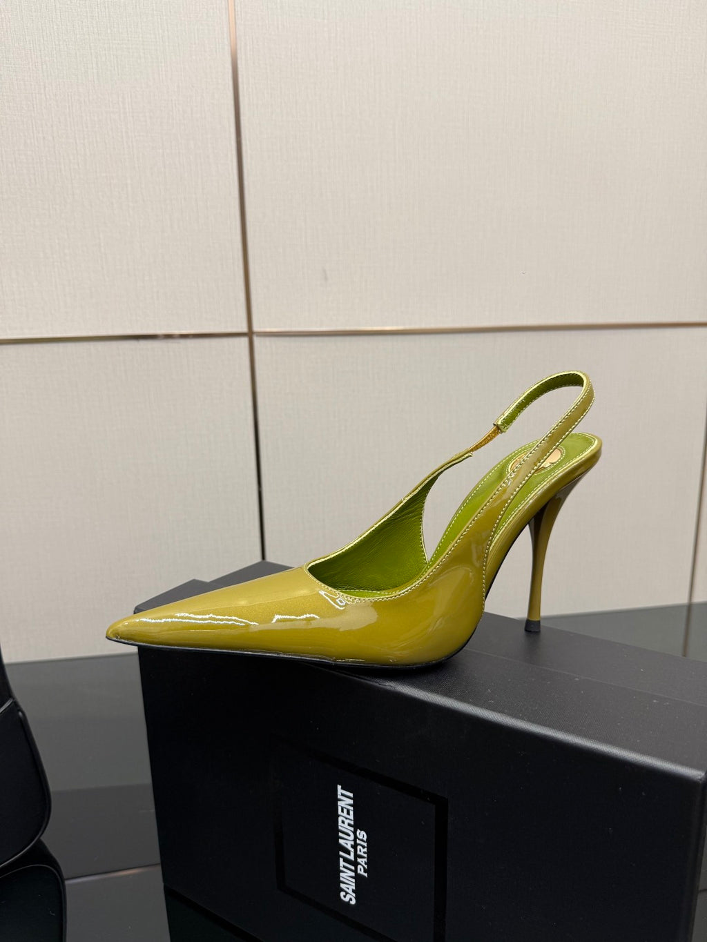 Lime-green patent pointed-toe slingback heel, single shoe profile on display box