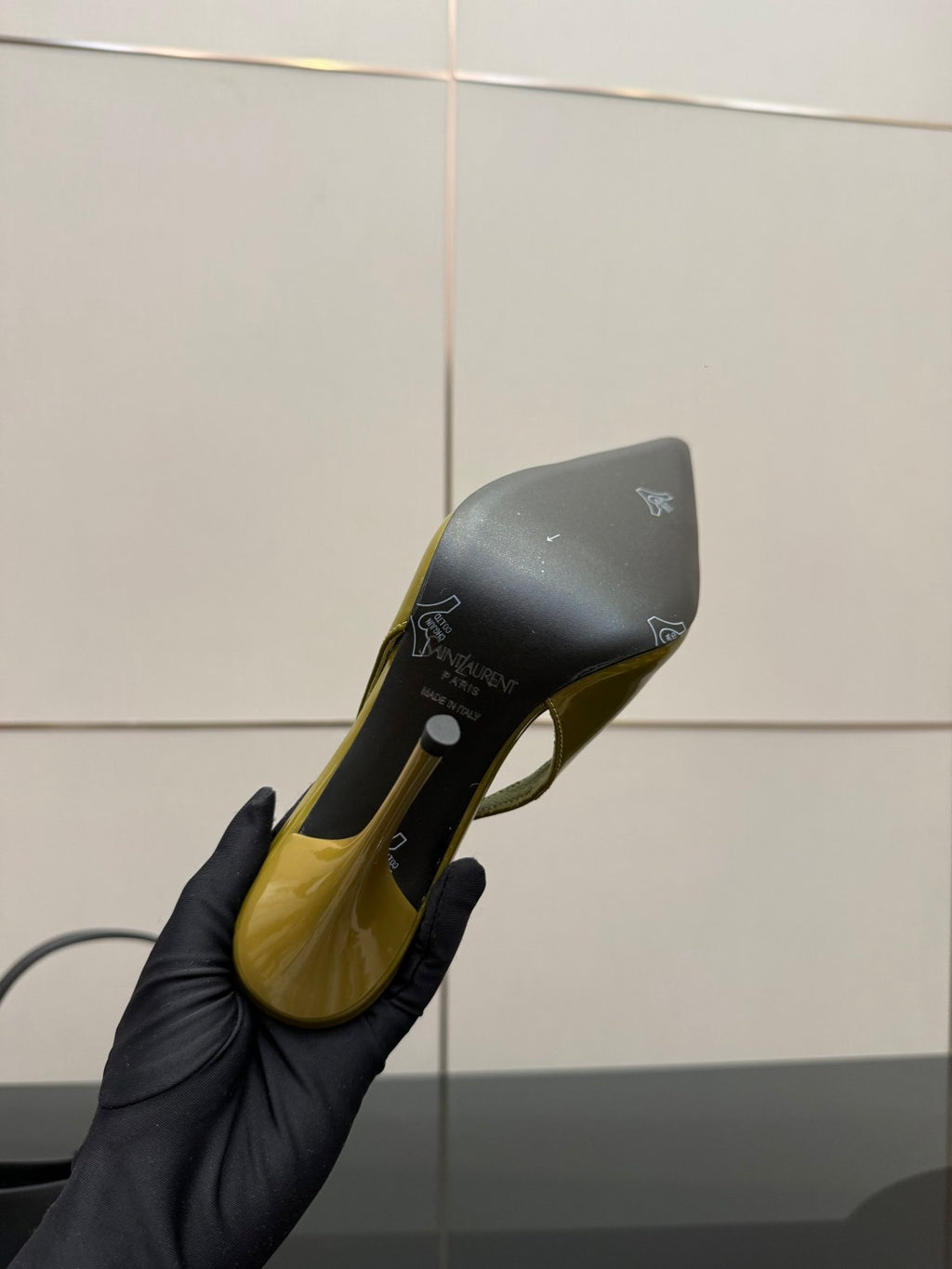 Lime-green patent heel sole and insole details on a glove-held pump