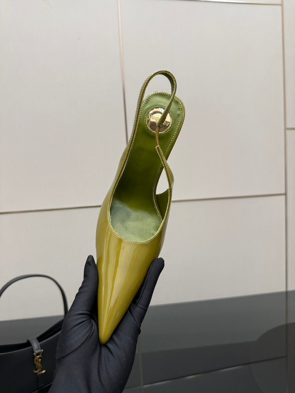 Lime-green patent slingback shoe with pointed toe, held upright showing strap opening