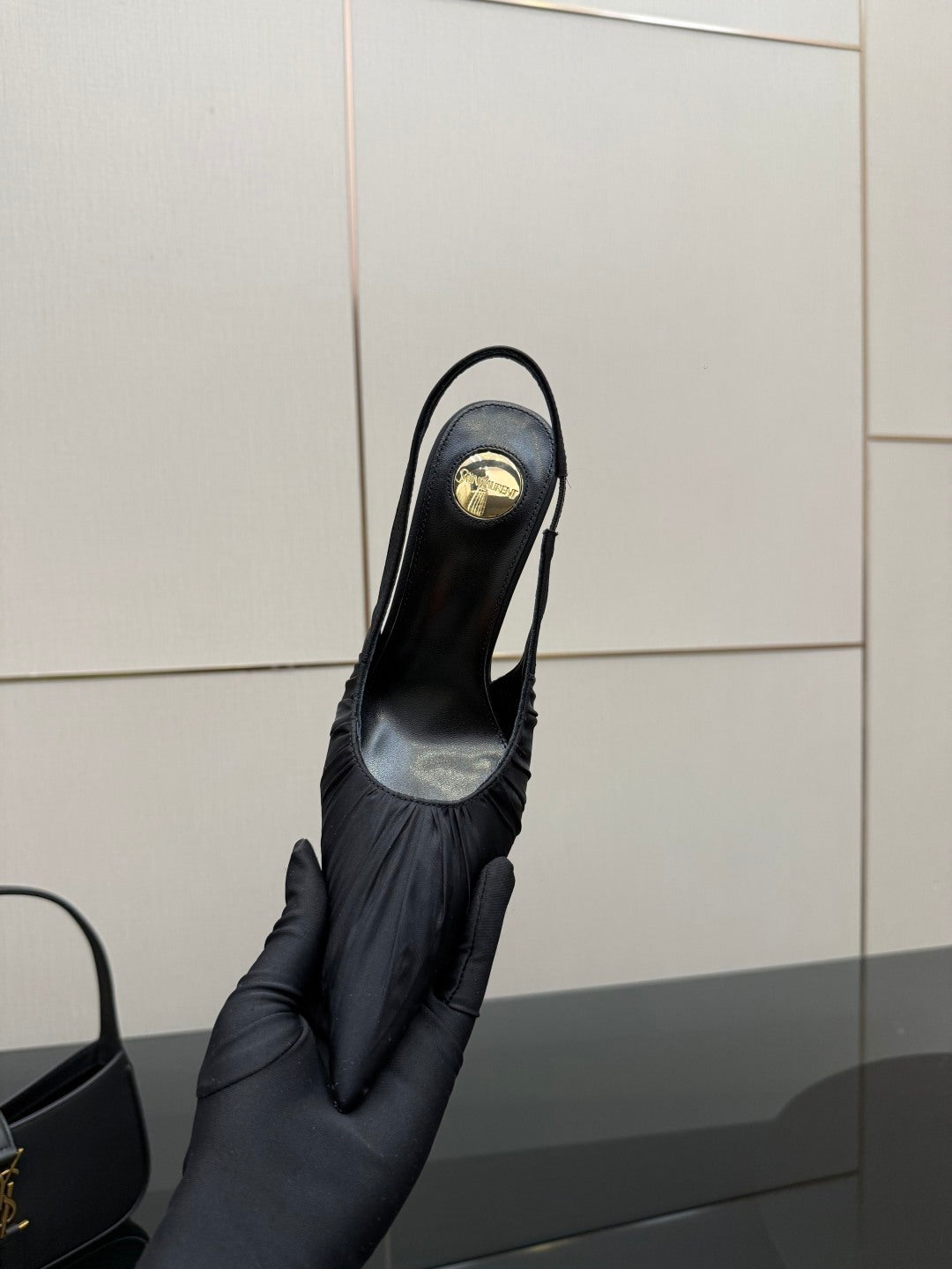 Black pointed-toe slingback high-heel shoe held up, back and heel view