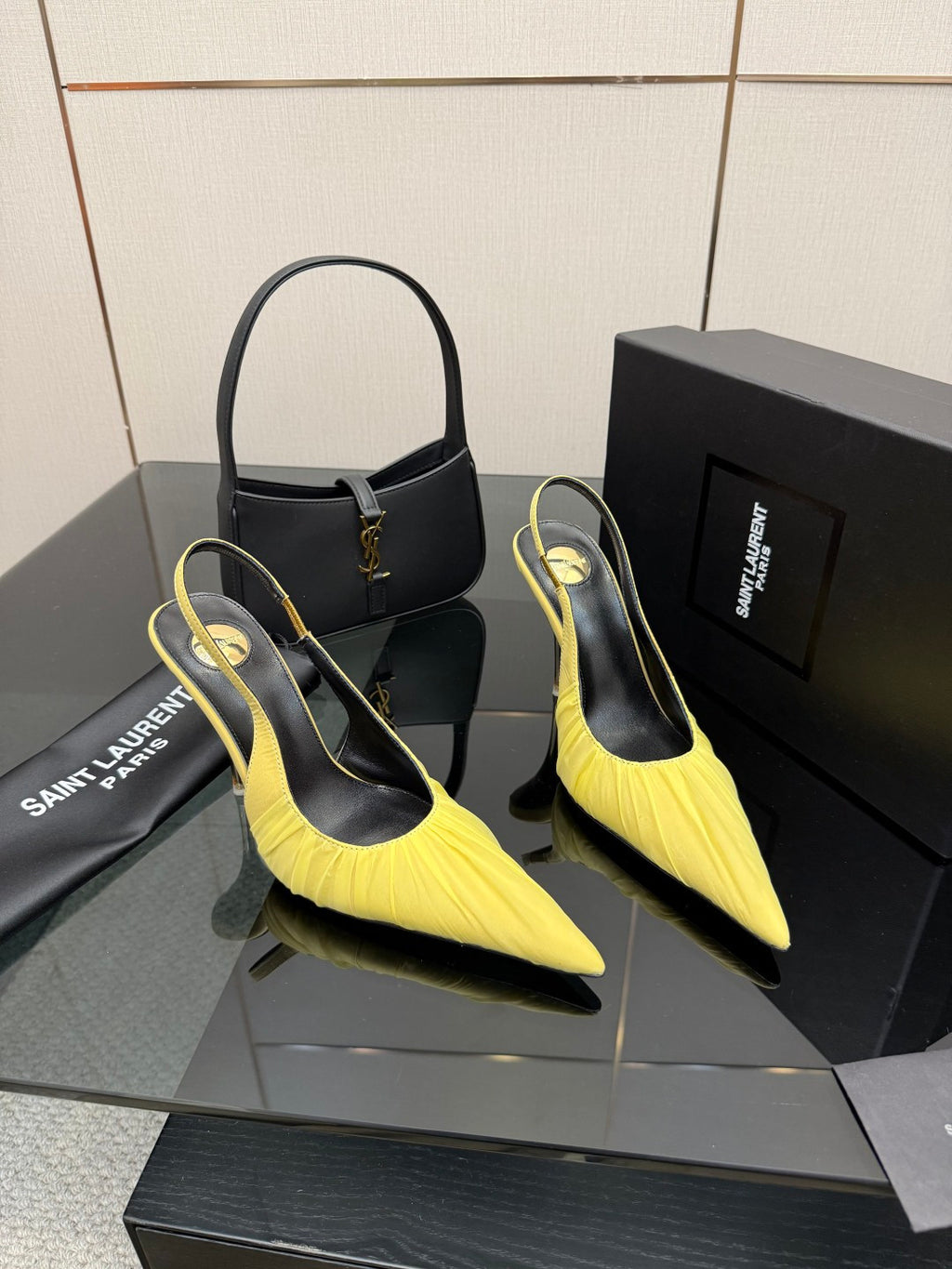 Pair of yellow pointed-toe slingback stiletto heels with black lining, resting on box