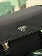 Black Prada bag close-up of front flap logo plate on smooth fabric.