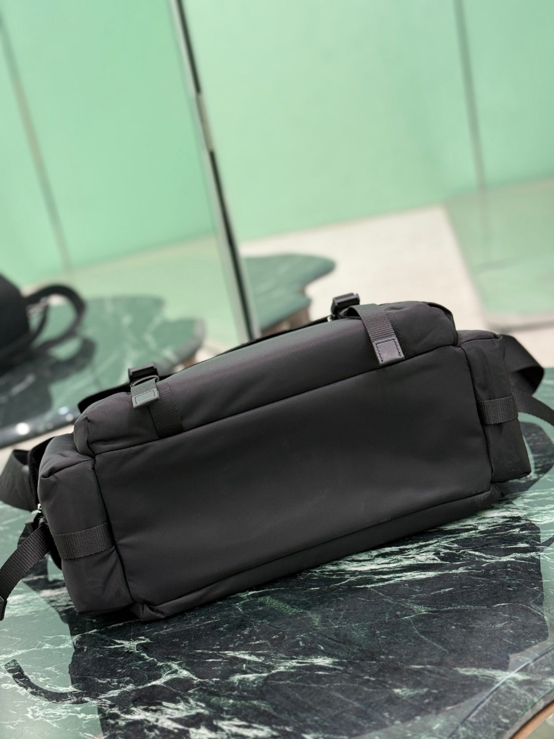 Black Prada bag back view with adjustable shoulder strap and top carry handle.