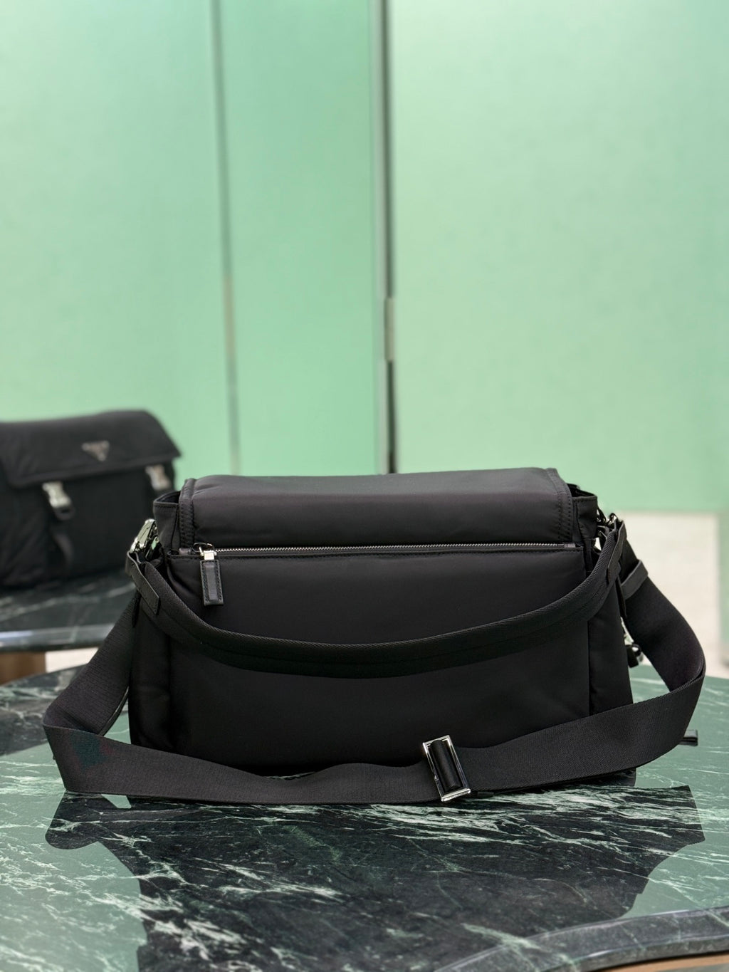 Black Prada crossbody bag with front flap, adjustable strap, and top handle.