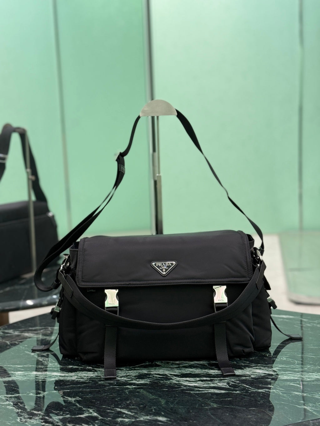 Black Prada messenger bag with front flap, logo plate, and crossbody strap.