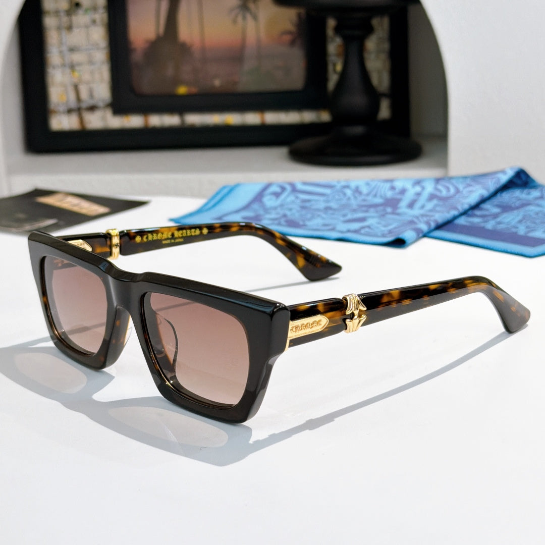 Black square sunglasses with gold-tone accents and tinted lenses; tortoiseshell temples