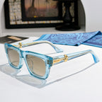 Light blue square sunglasses with tinted lenses and gold-tone logo detail on arms