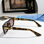 Tortoiseshell square sunglasses with pink-tinted lenses and gold-tone logo on arms