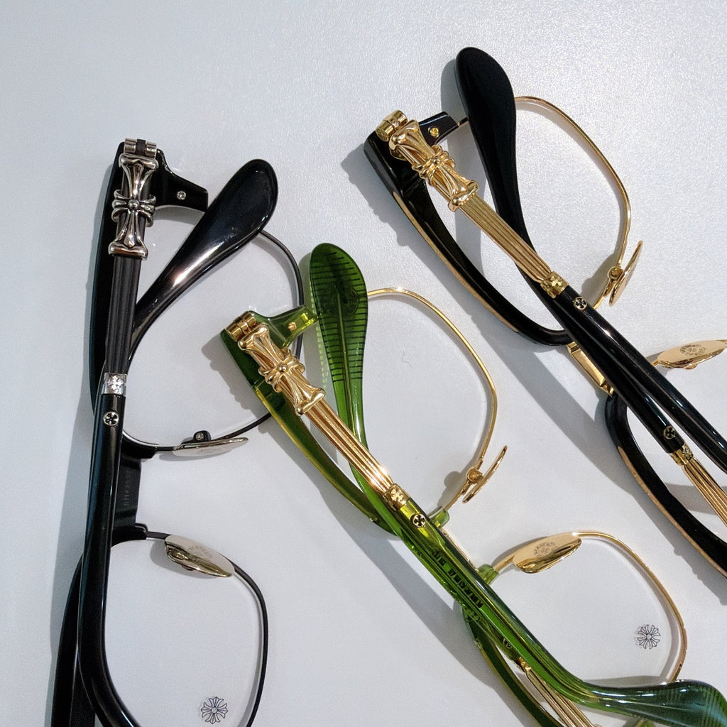 Assorted eyeglasses with clear lenses: black, green, and gold-toned frames