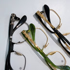 Assorted eyeglasses with clear lenses: black, green, and gold-toned frames