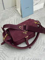 Burgundy suede Prada shoulder bag with front flap, gold buckle, and curved strap