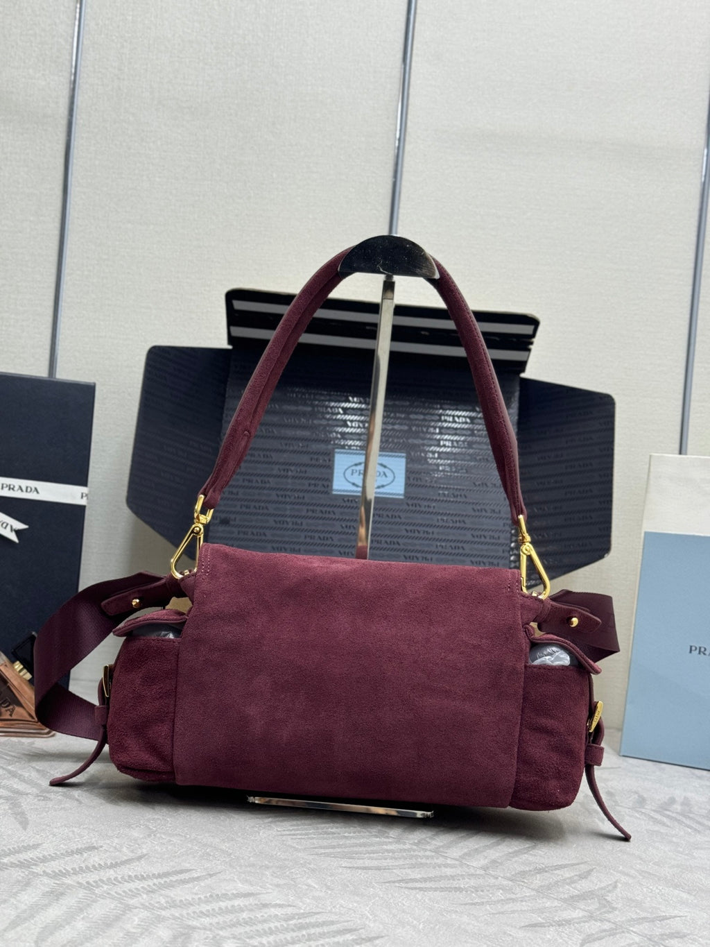 Burgundy suede Prada tote-style bag with top handles, flap front, and gold trim