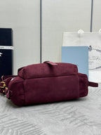 Burgundy suede Prada bag with rounded top, flap front, and gold-tone hardware