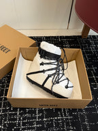 White and black lace-up snow boot with black strap at the ankle and laces